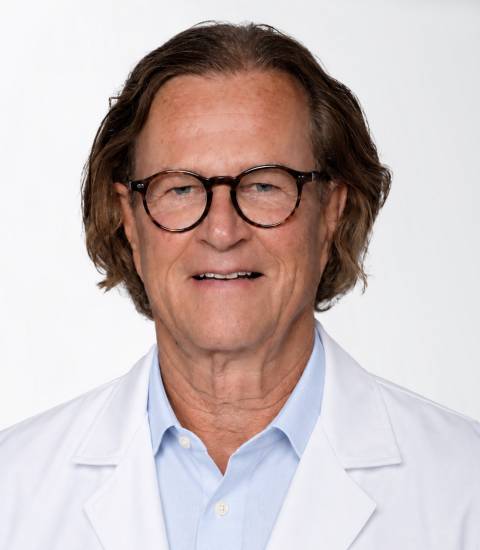 Dr. med. Wilhelm Knarr, ein Mann in weißem Arztkittel in hellen Praxisräumen